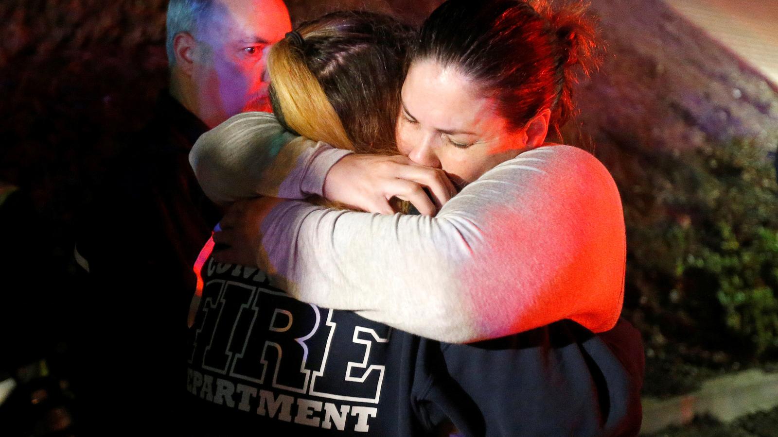 A young woman in tears hugs a police officer.