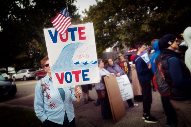A voter carries a 'blue wave' poster at a rally