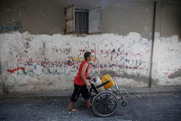 Gaza boy pushing wheelchair water
