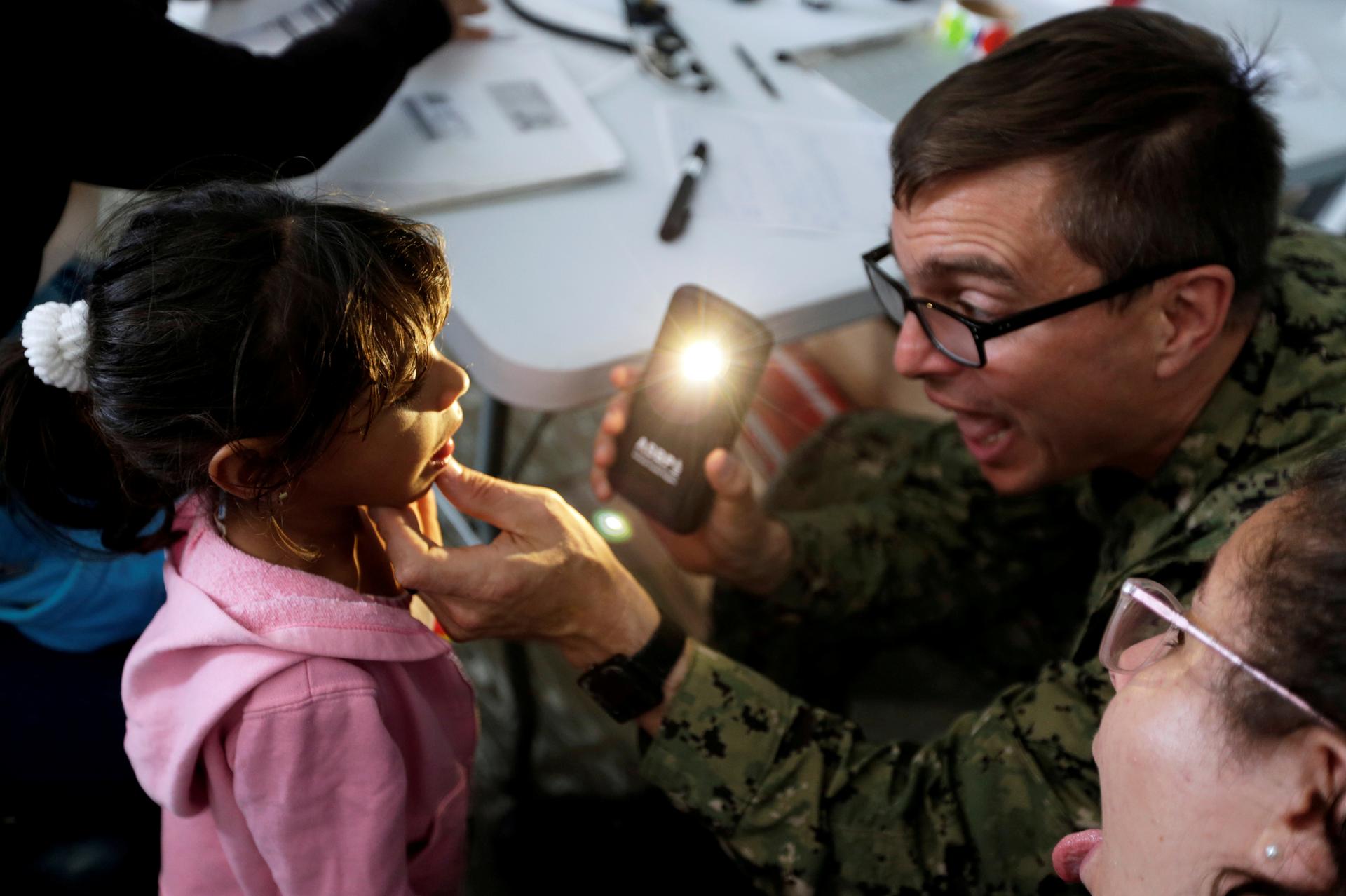 a doctor shining a light into a young girl's mouth