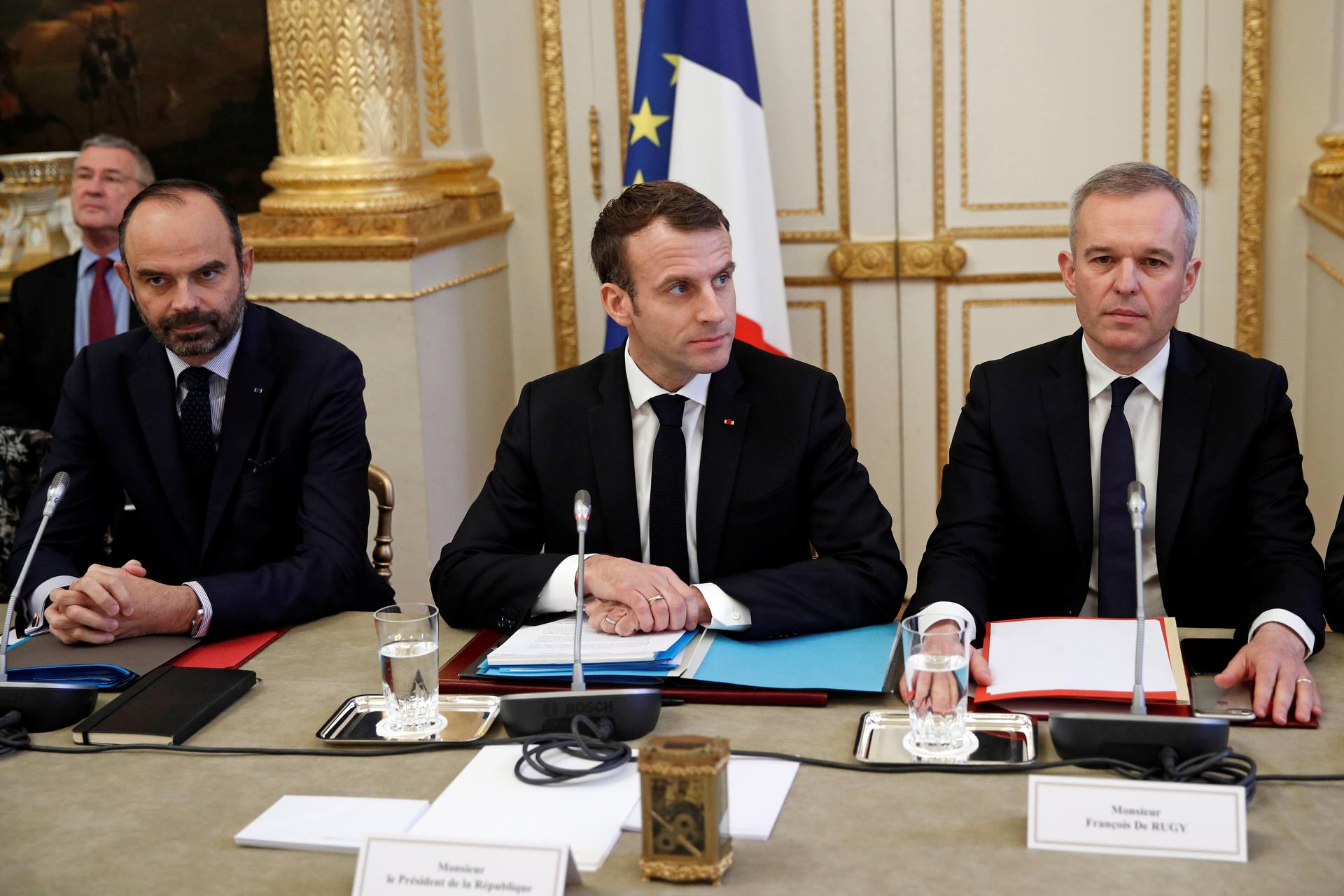 French President Emmanuel Macron, French Prime Minister Edouard Philippe, left, and French Ecology Minister Francois de Rugy dressed in suits and sitting behind a table
