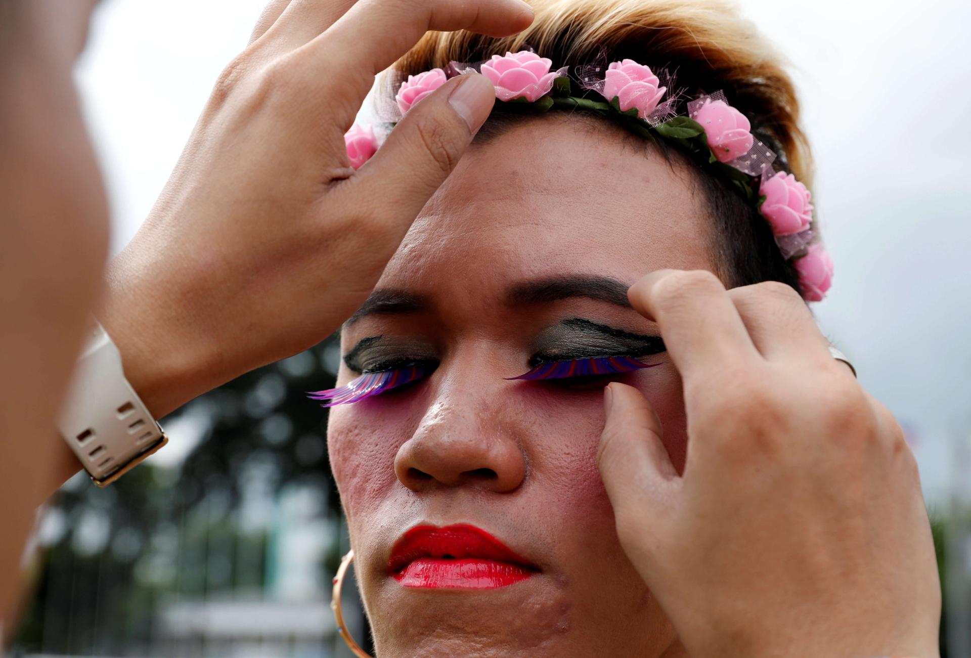 a closeup of a transgender participant with bright red lipstick and thick, fake eyelashes