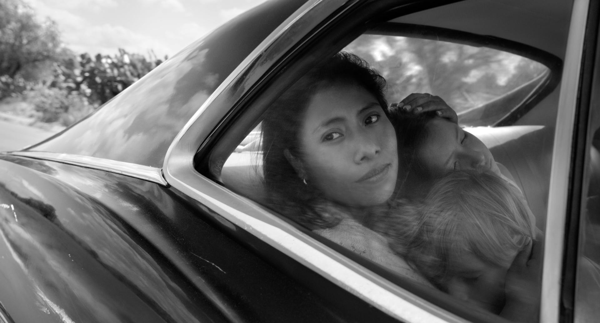 a black and white photo of a woman looking out a car window