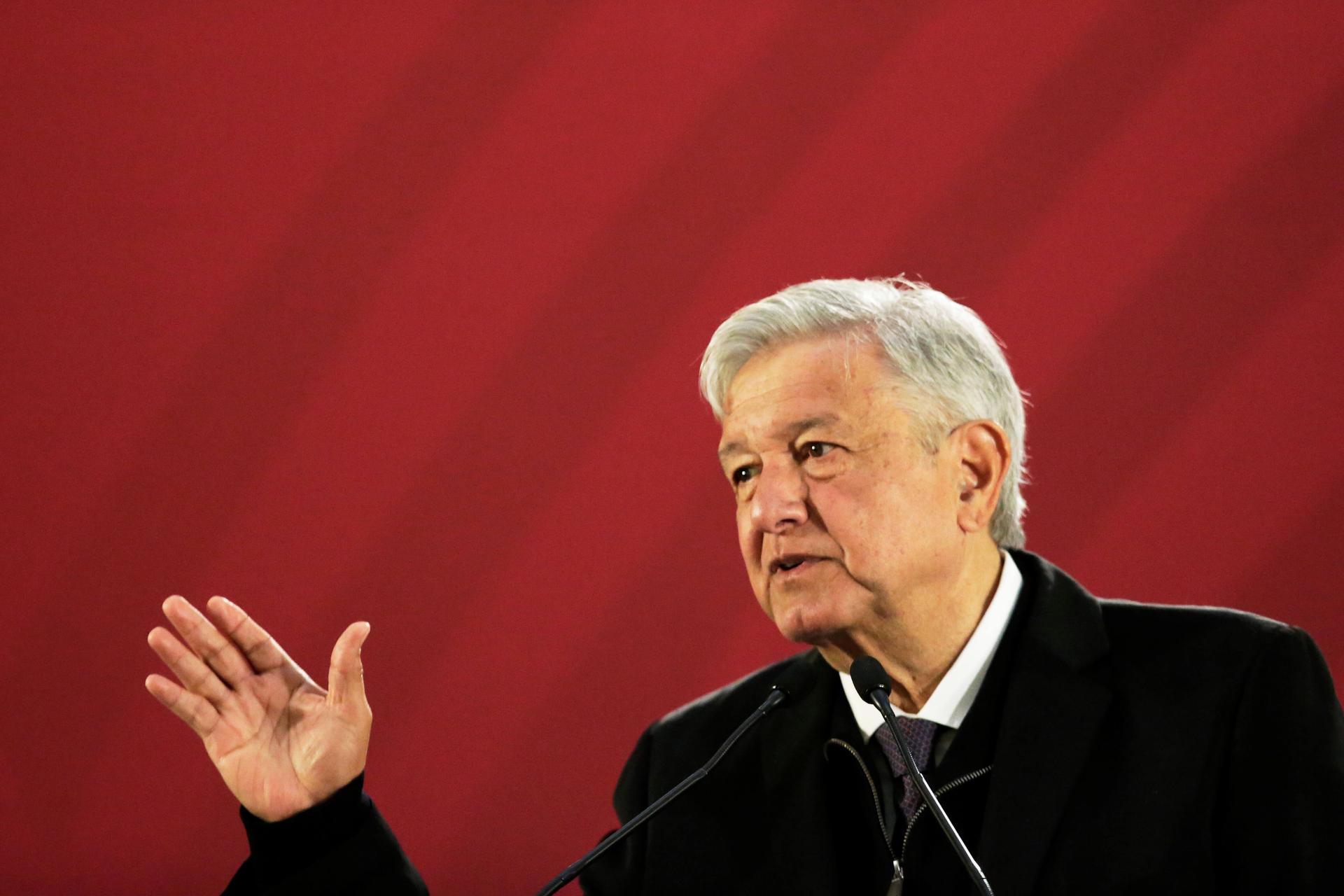 Mexico's President Andres Manuel Lopez Obrador gesturing in front of a red background