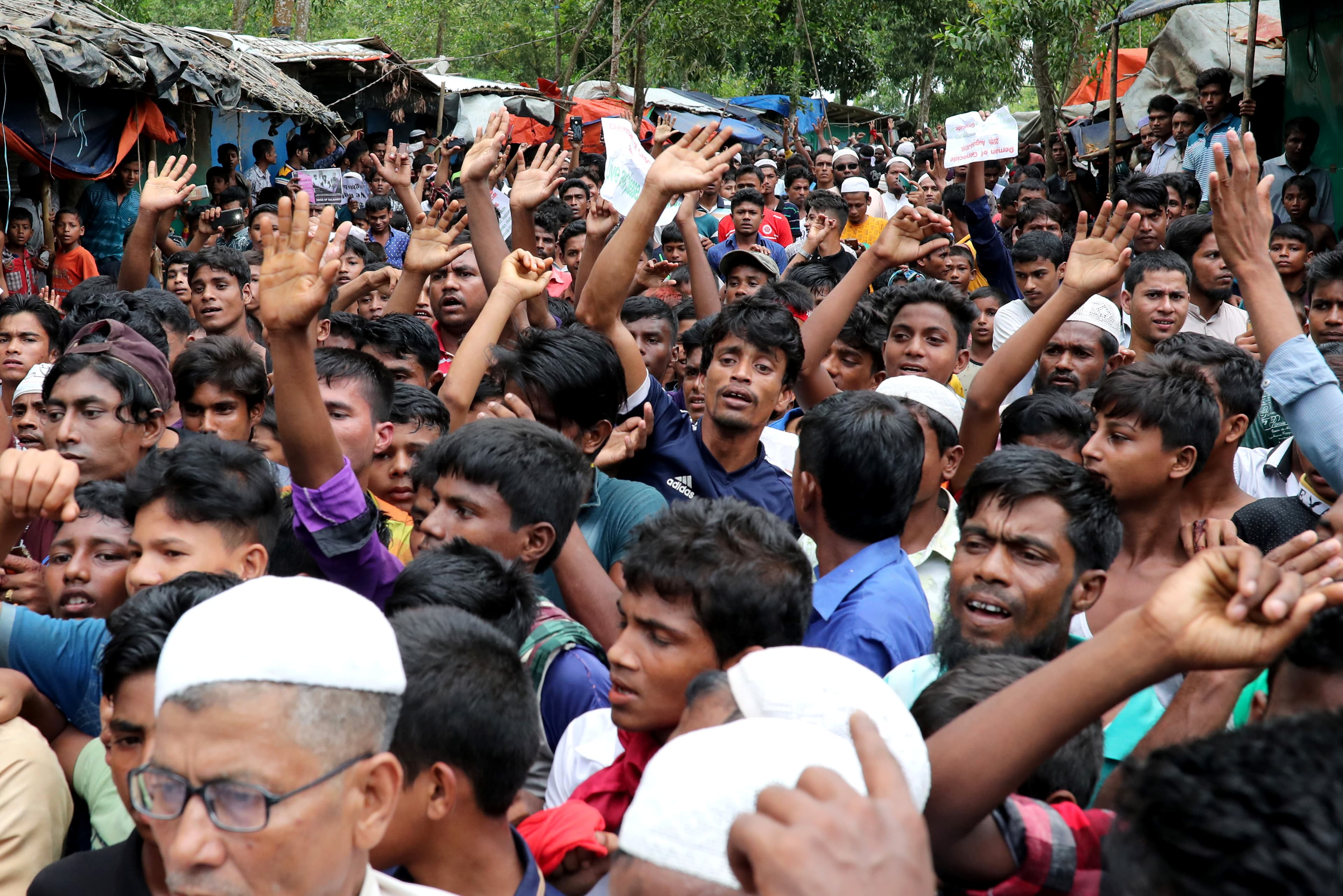 a large group of Rohingya refugees shout slogans