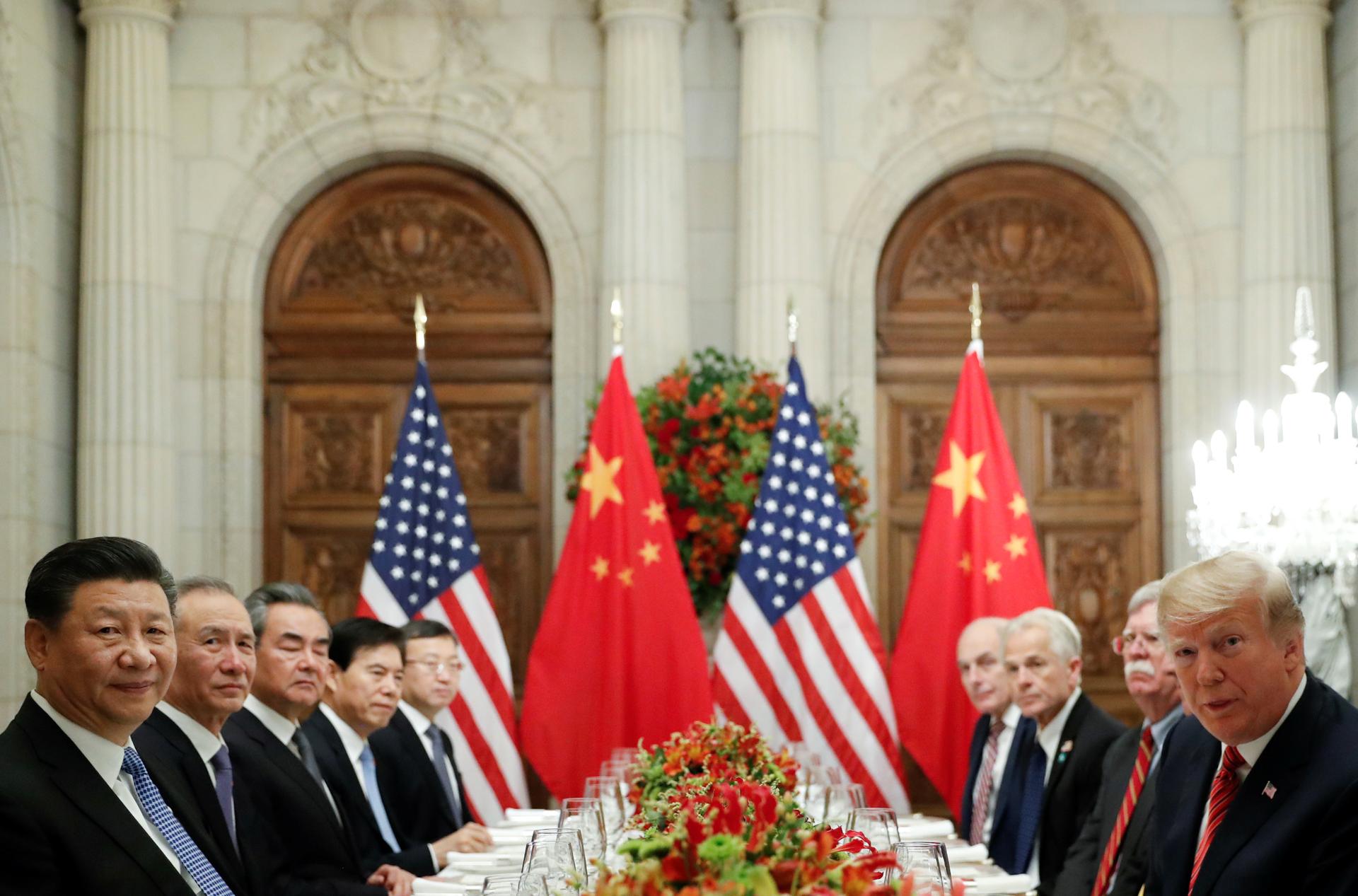 US President Donald Trump, Chinese President Xi Jinping and other leaders all sit around a table, looking at the camera