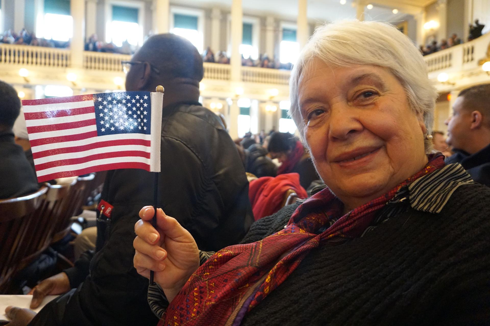 a close up on Natalia Malkes waving a small flag during her citizenship ceremony