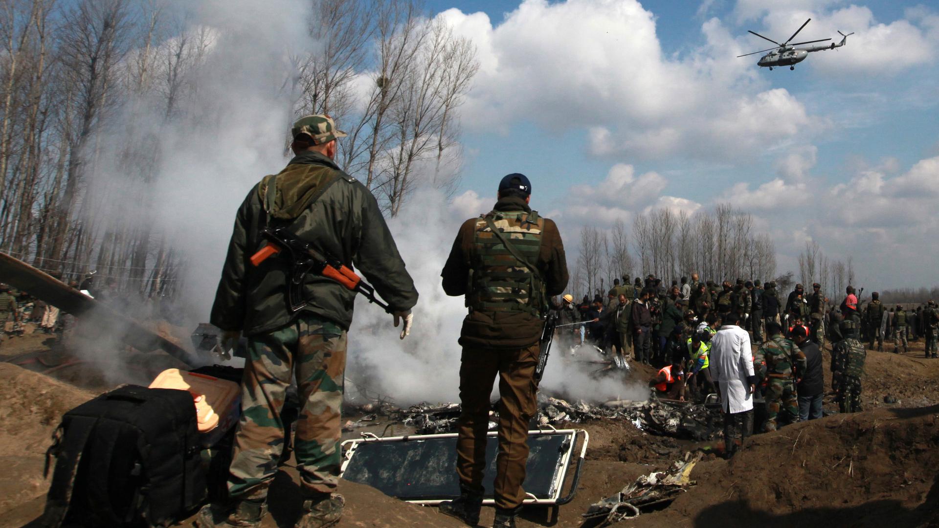 Indian soldiers stand next to the wreckage of Indian Air Force's helicopter