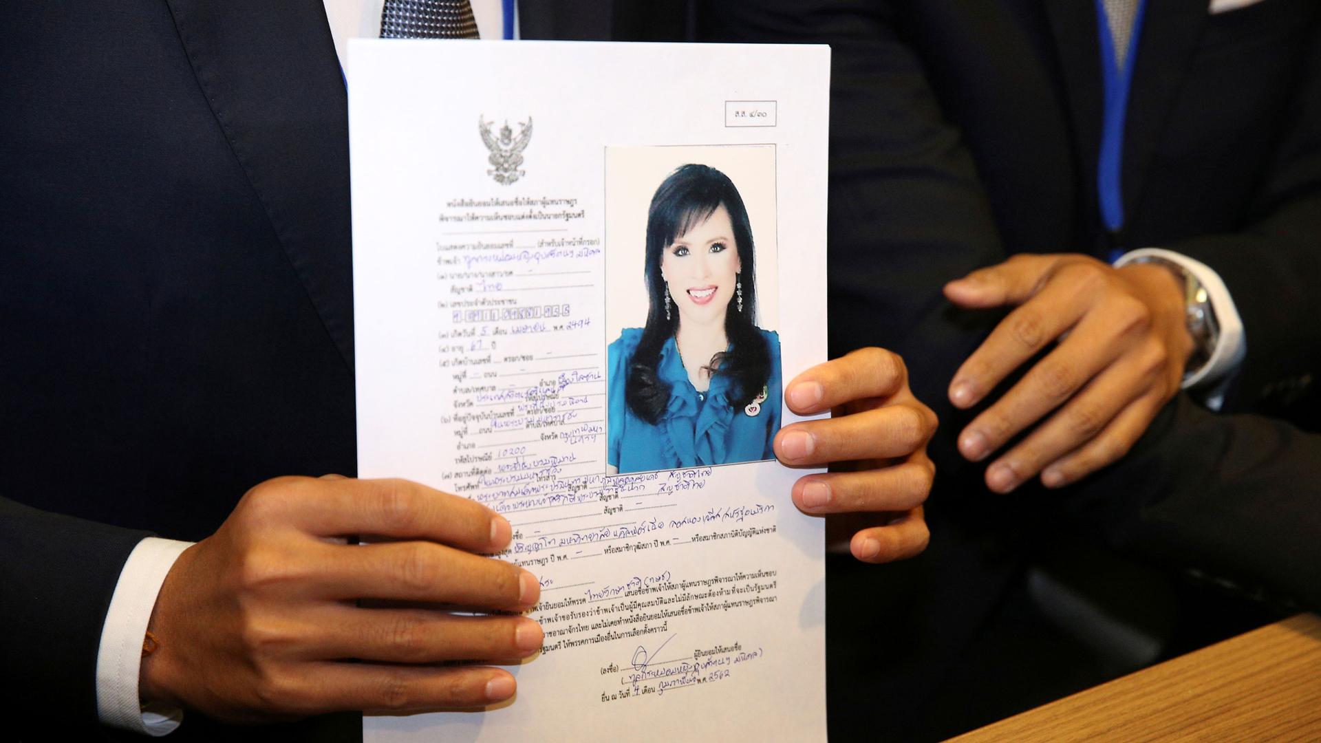 A woman's headshot is taped to a form as a man holds it in front of him.