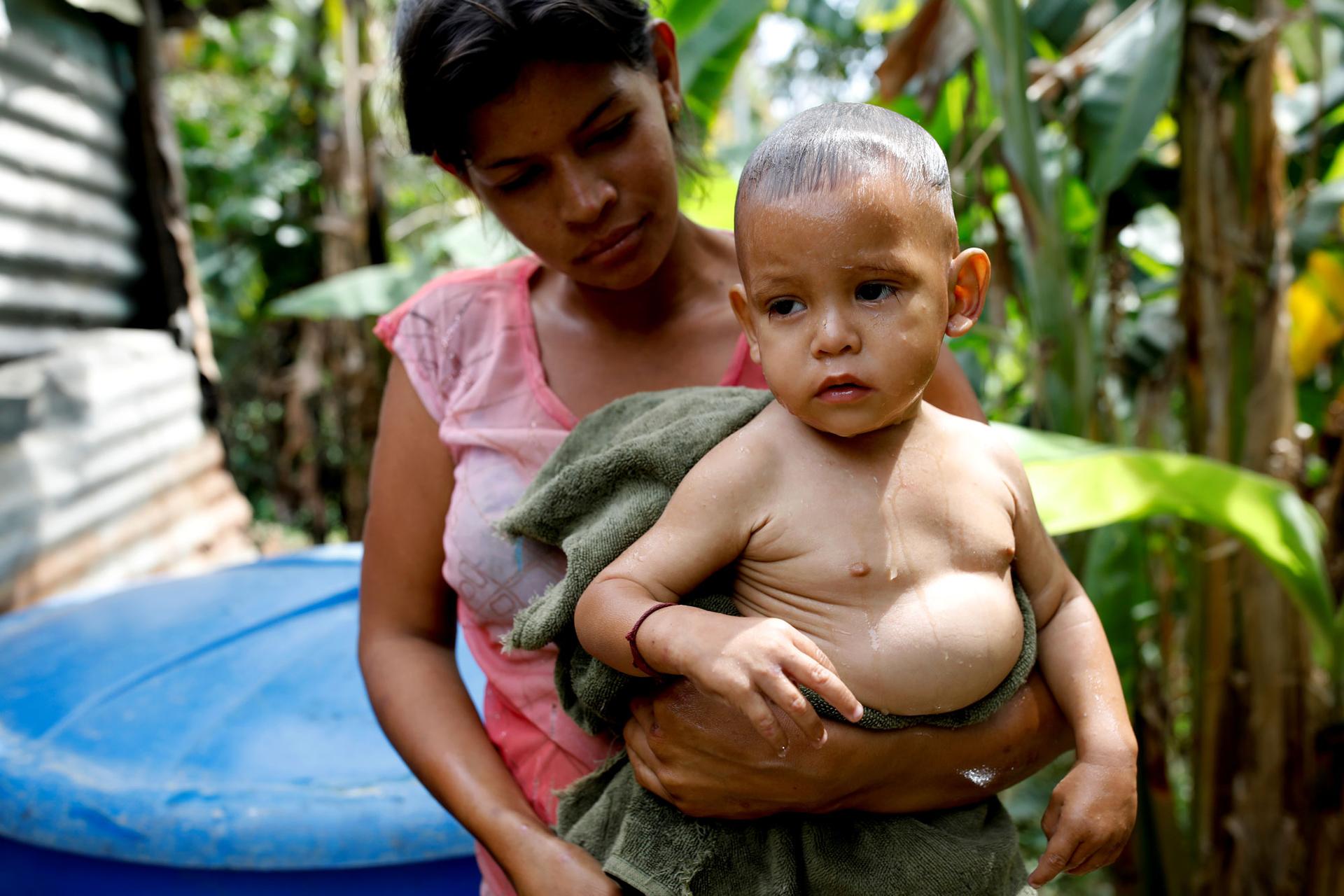 Maria Guitia is shown carrying her son Yeibe Medina, still wet from a bath.