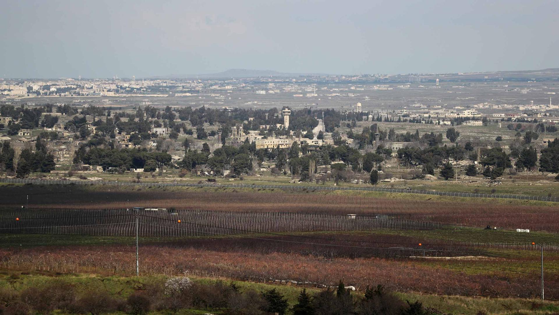 A view of buildings is seen a a border fence