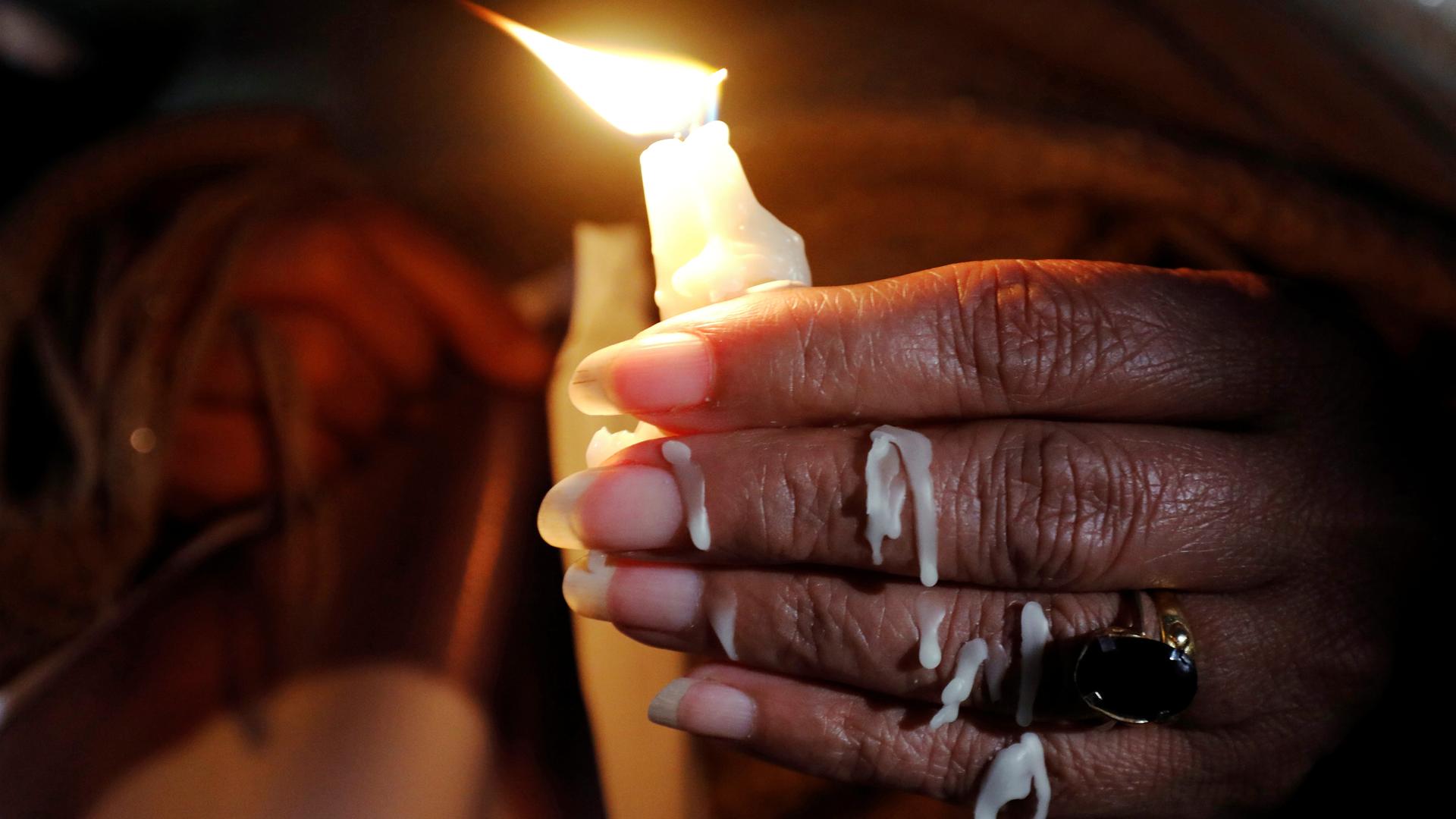 wax drips down a woman hand as she holds a candle