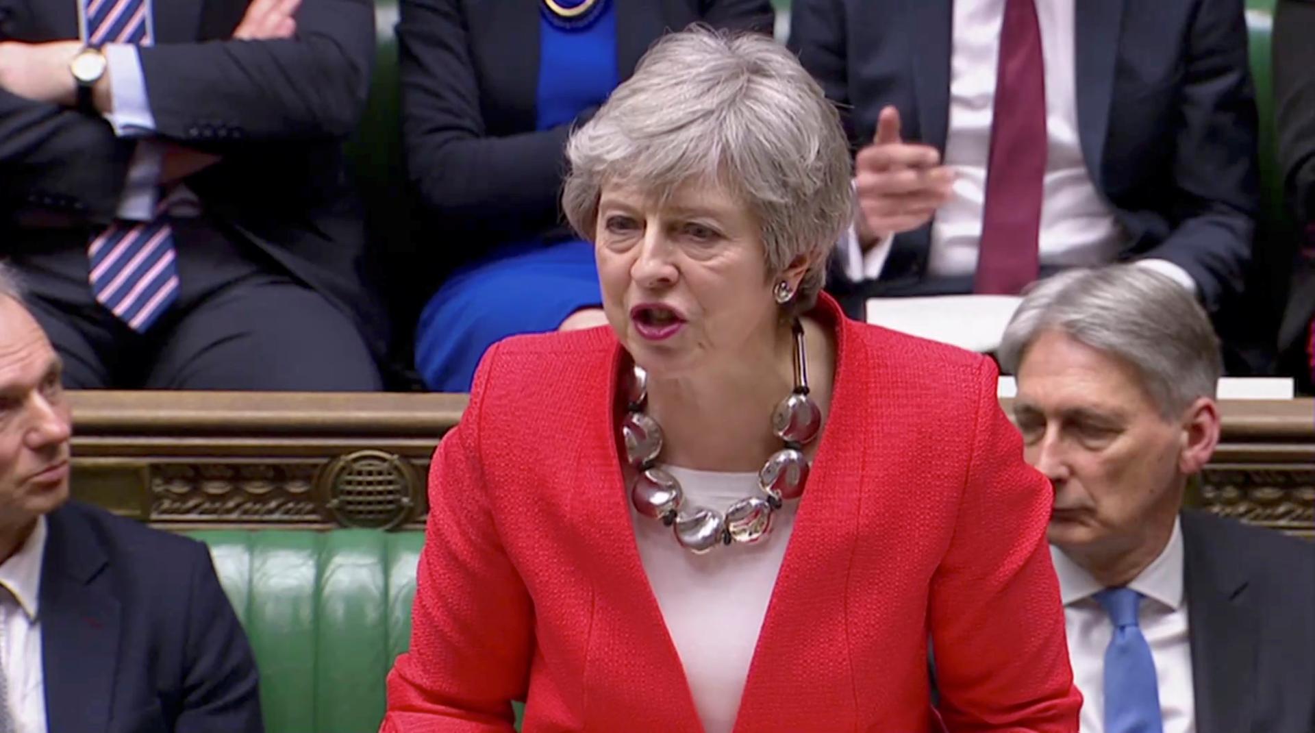 Theresa May in red suit in parliament.