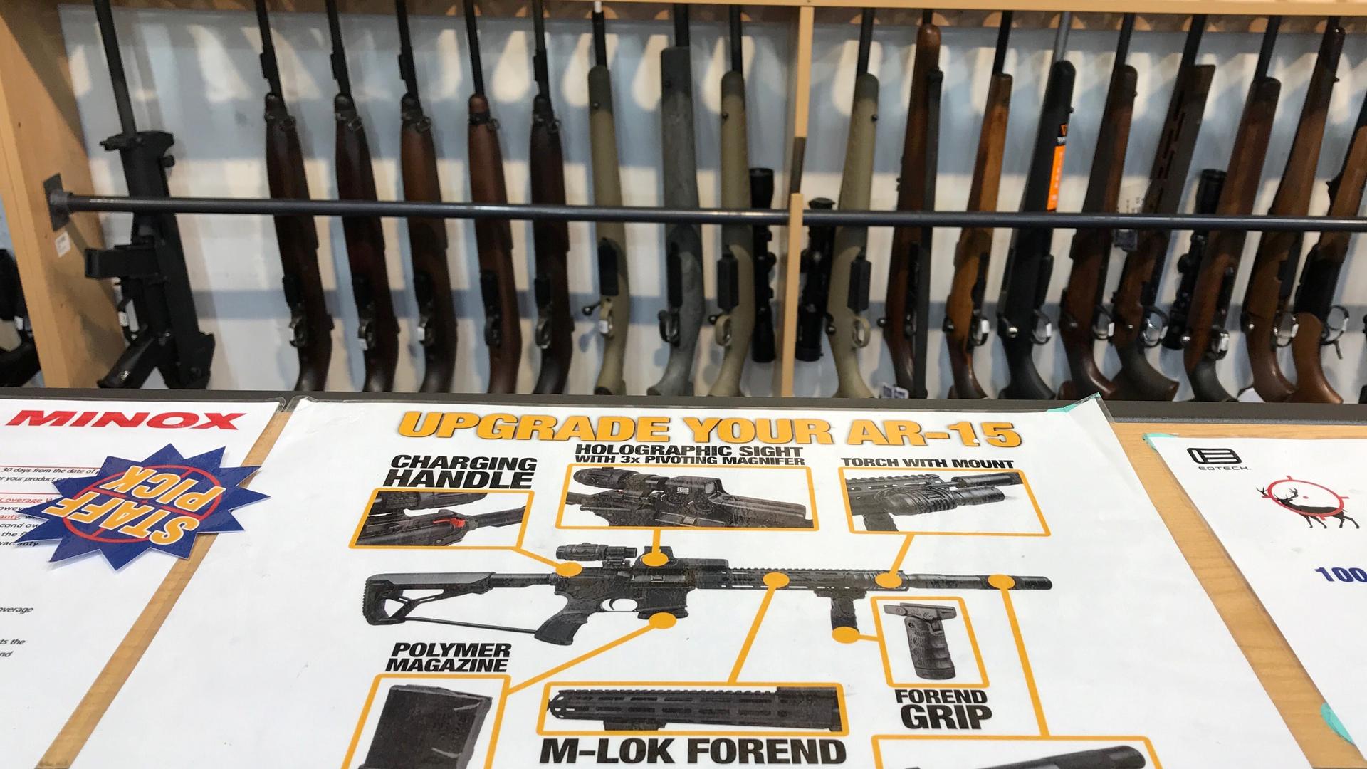 guns lined up by an advertisement for AR 15