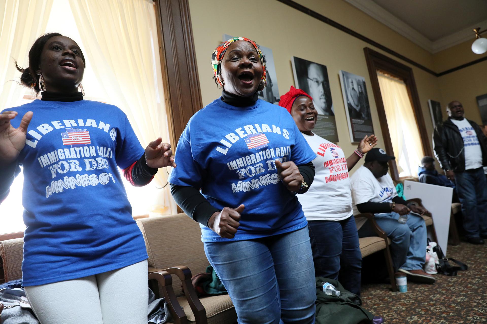 Women in blue and white shirts dance and sing.