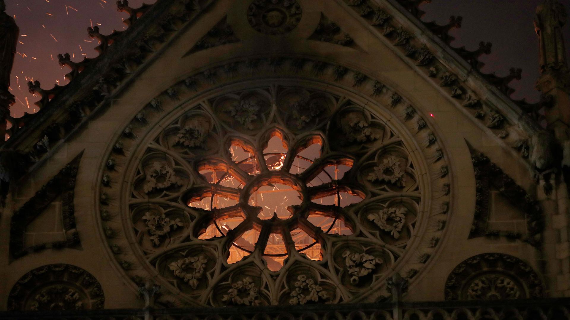 Sparks are seen through one of Notre-Dame's iconic stained glass windows.