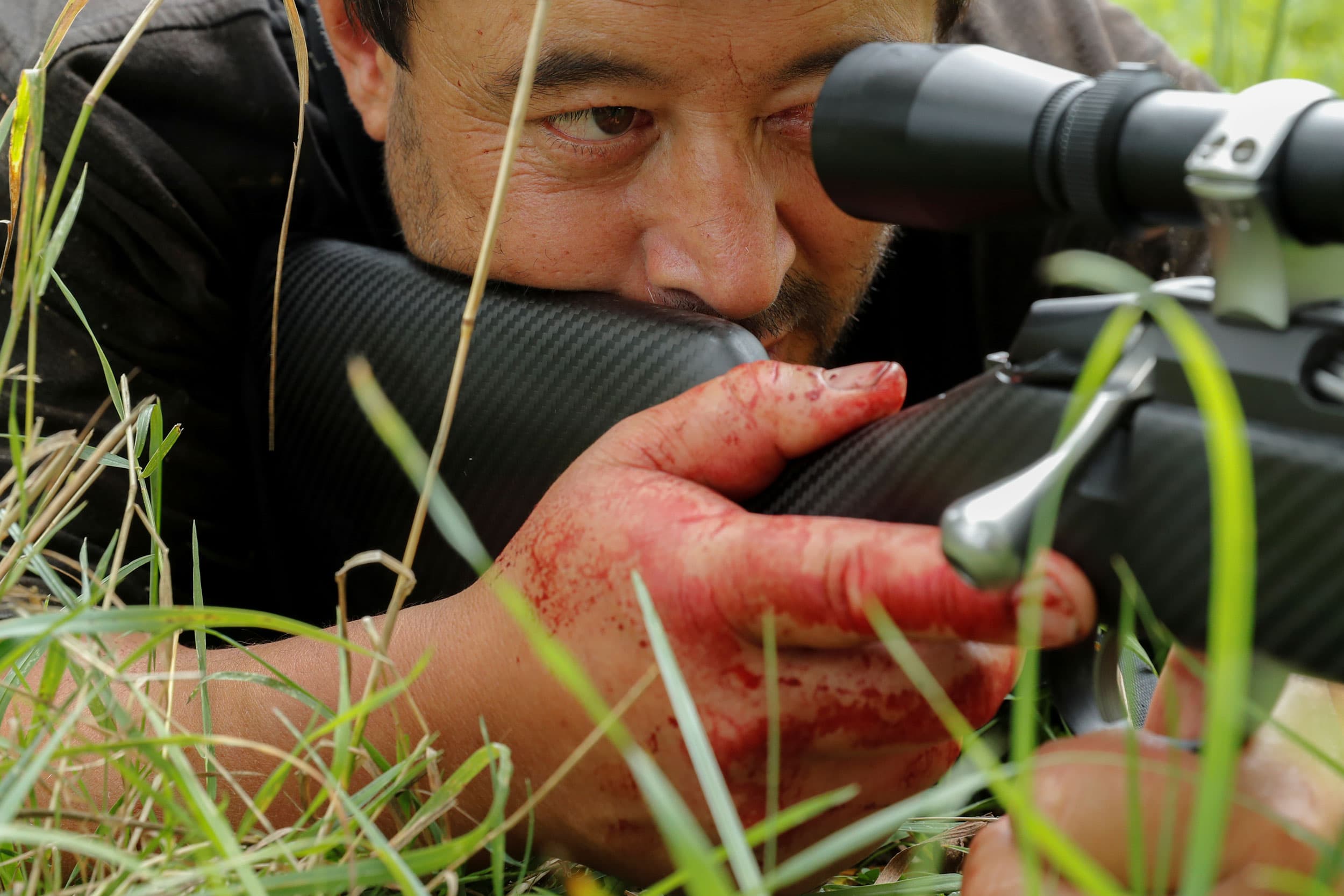 Noel Womersley is shown in a close-up photo laying down with his bloodied-hand around his gun.