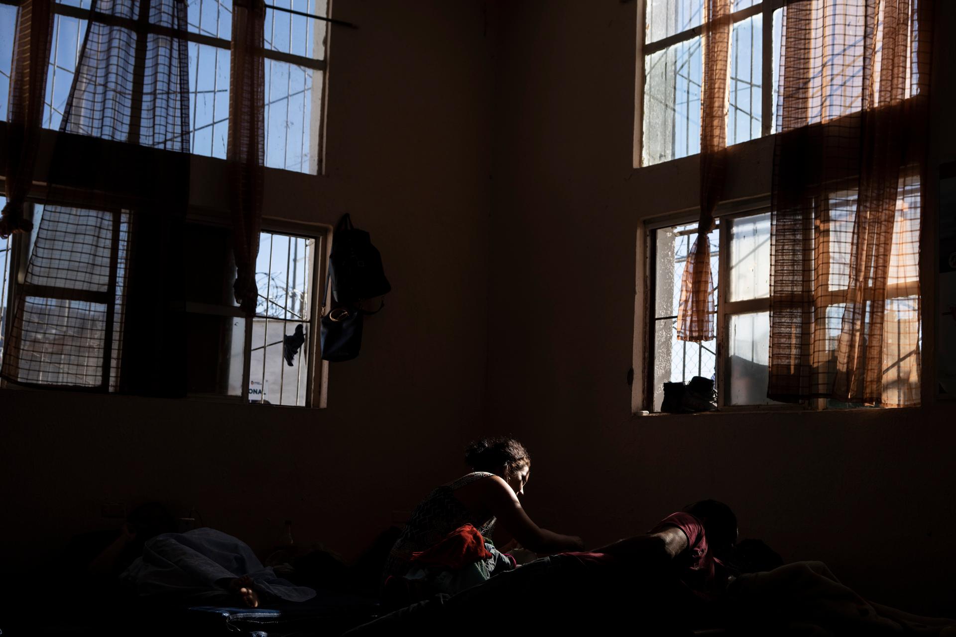 People rest in a shelter as light spills in from a window