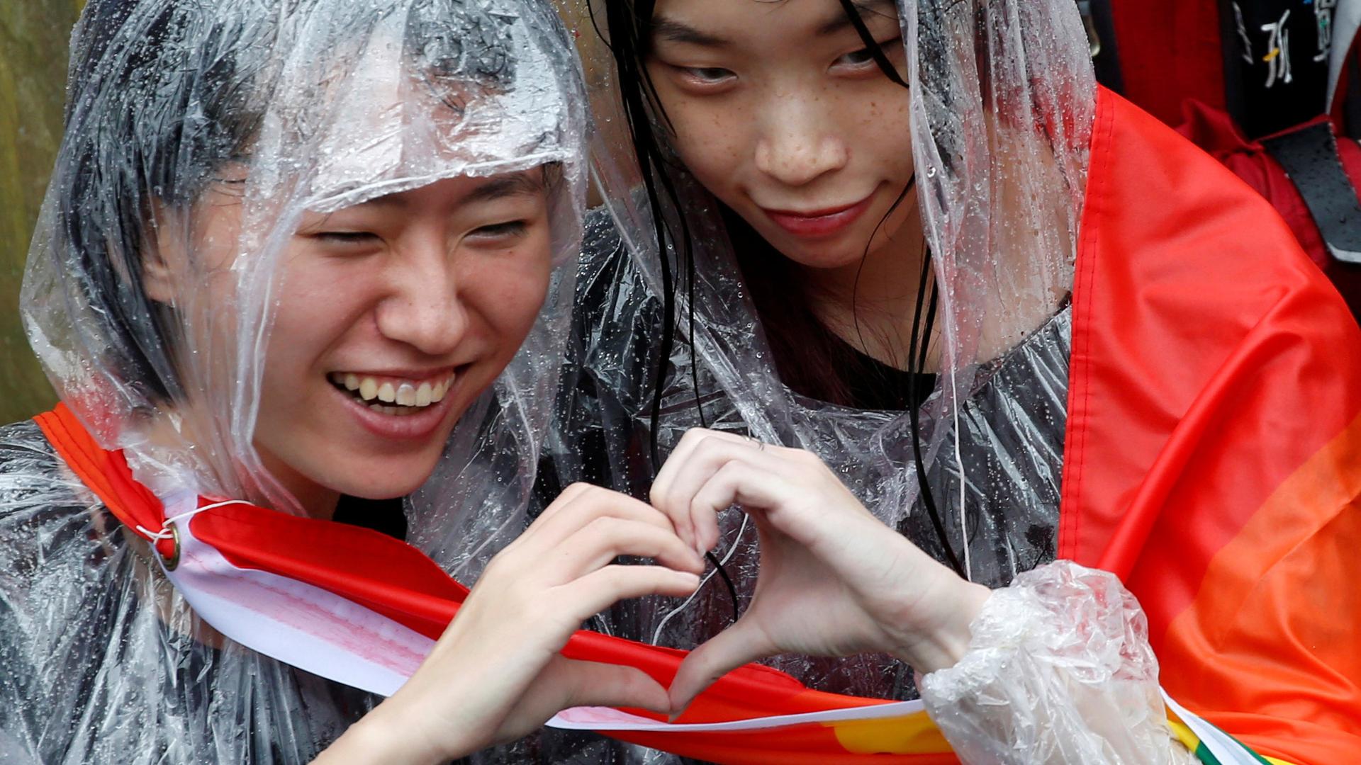 Two women make the shape of a heart with their hands