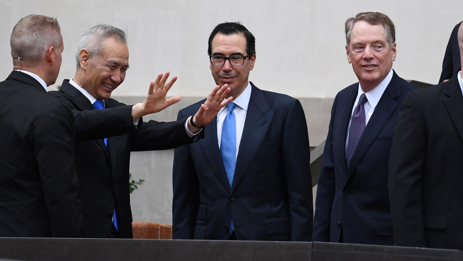 Chinese Vice Premier Liu He is shown with his hands outstretched and smiling next to Treasury Secretary Steven Mnuchin and Trade Representative Robert Lighthizer.