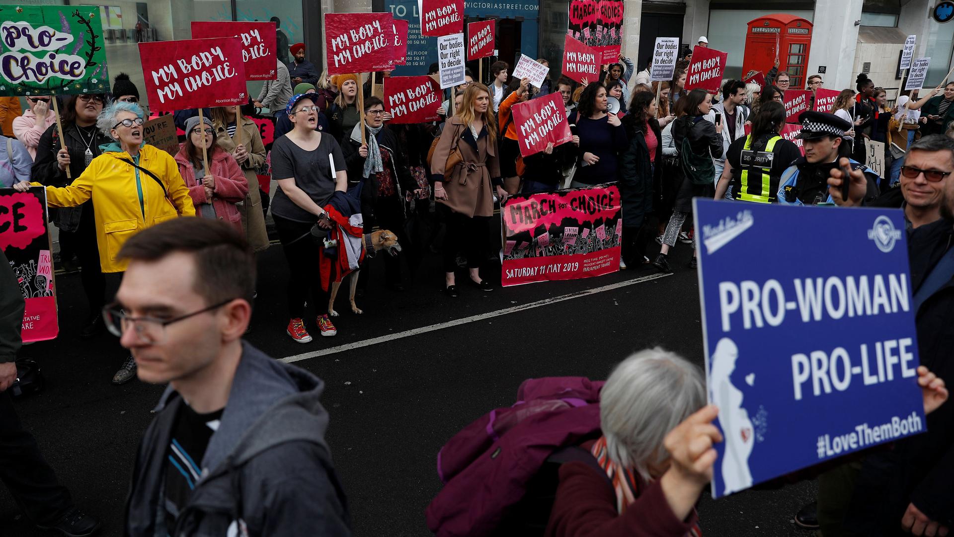 Pro-abortion and anti-abortion demonstrators are shown with colorful placards arguing their position.