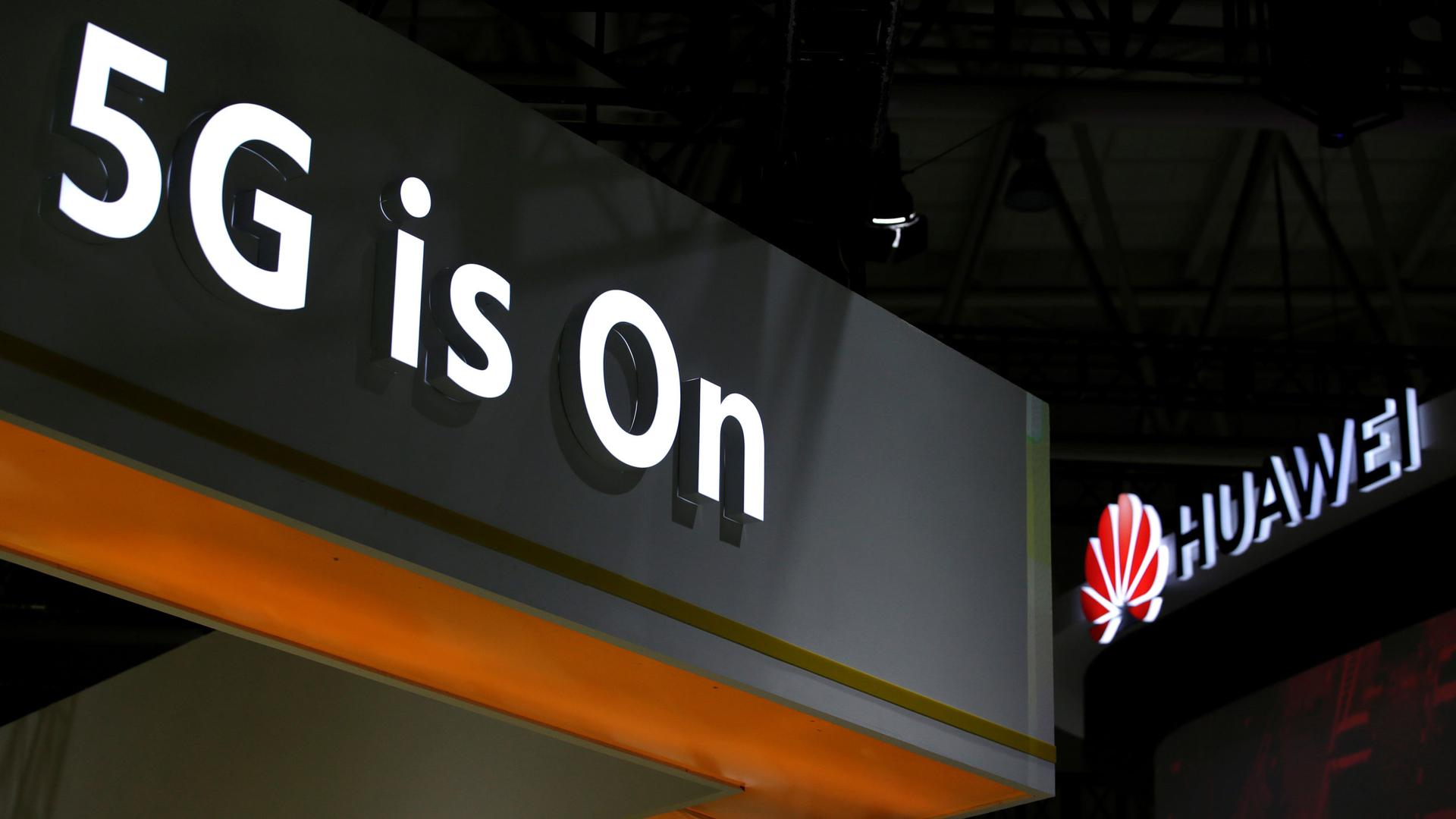 A photo showing the corner of a exhibition booth with the words, "5G is On" illuminated in white.