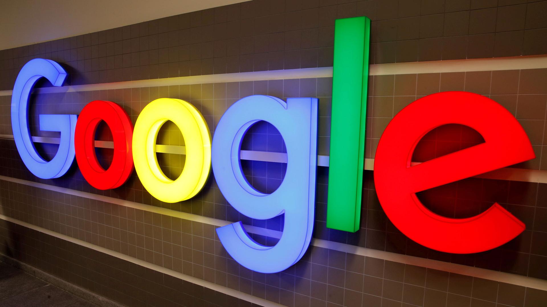 With letters that take up the entire frame of the photo, an illuminated Google logo is shown against a tile backdrop.