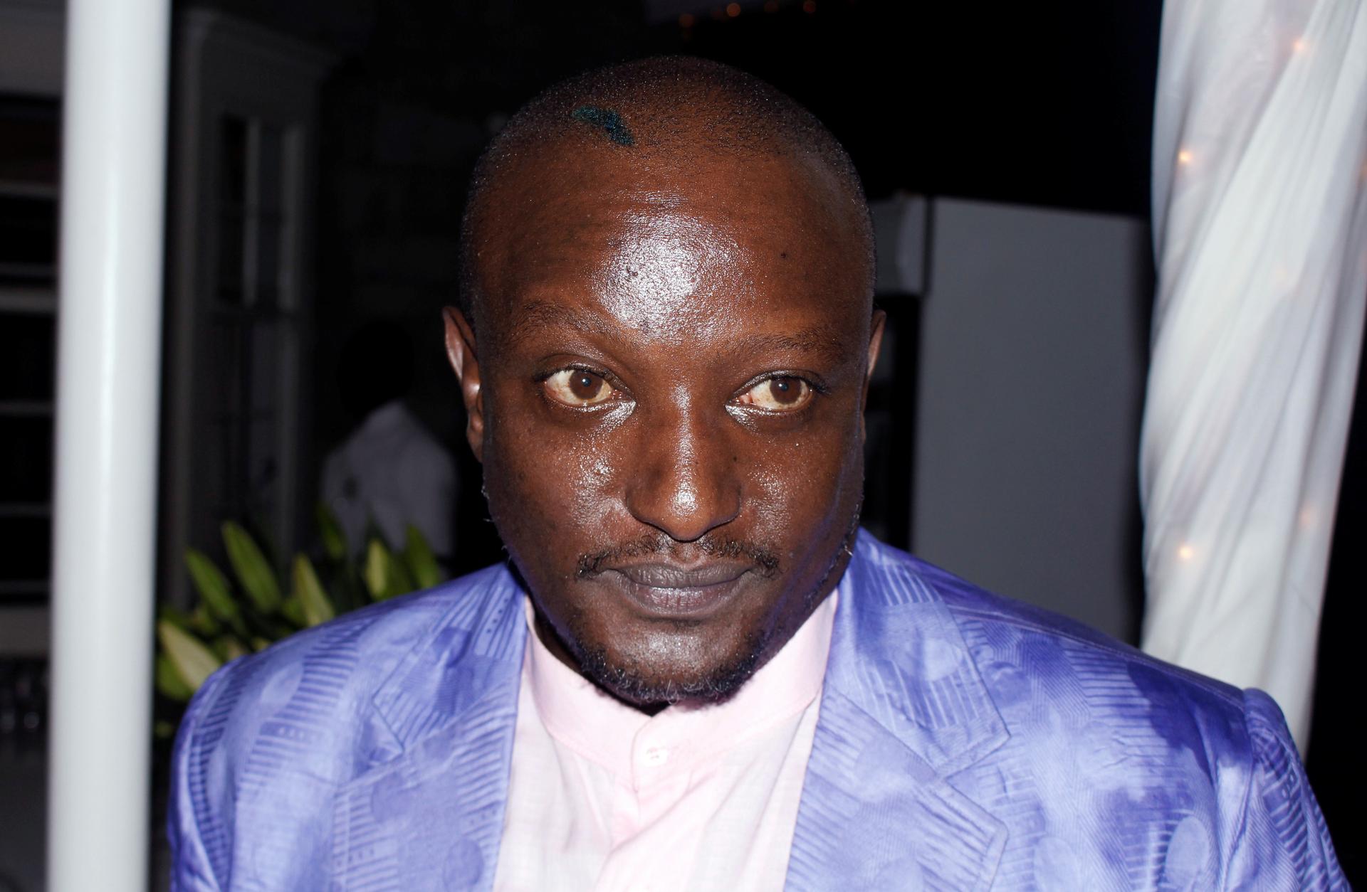 Portrait of the late Binyavanga Wainaina in shiny purple suit with white shirt