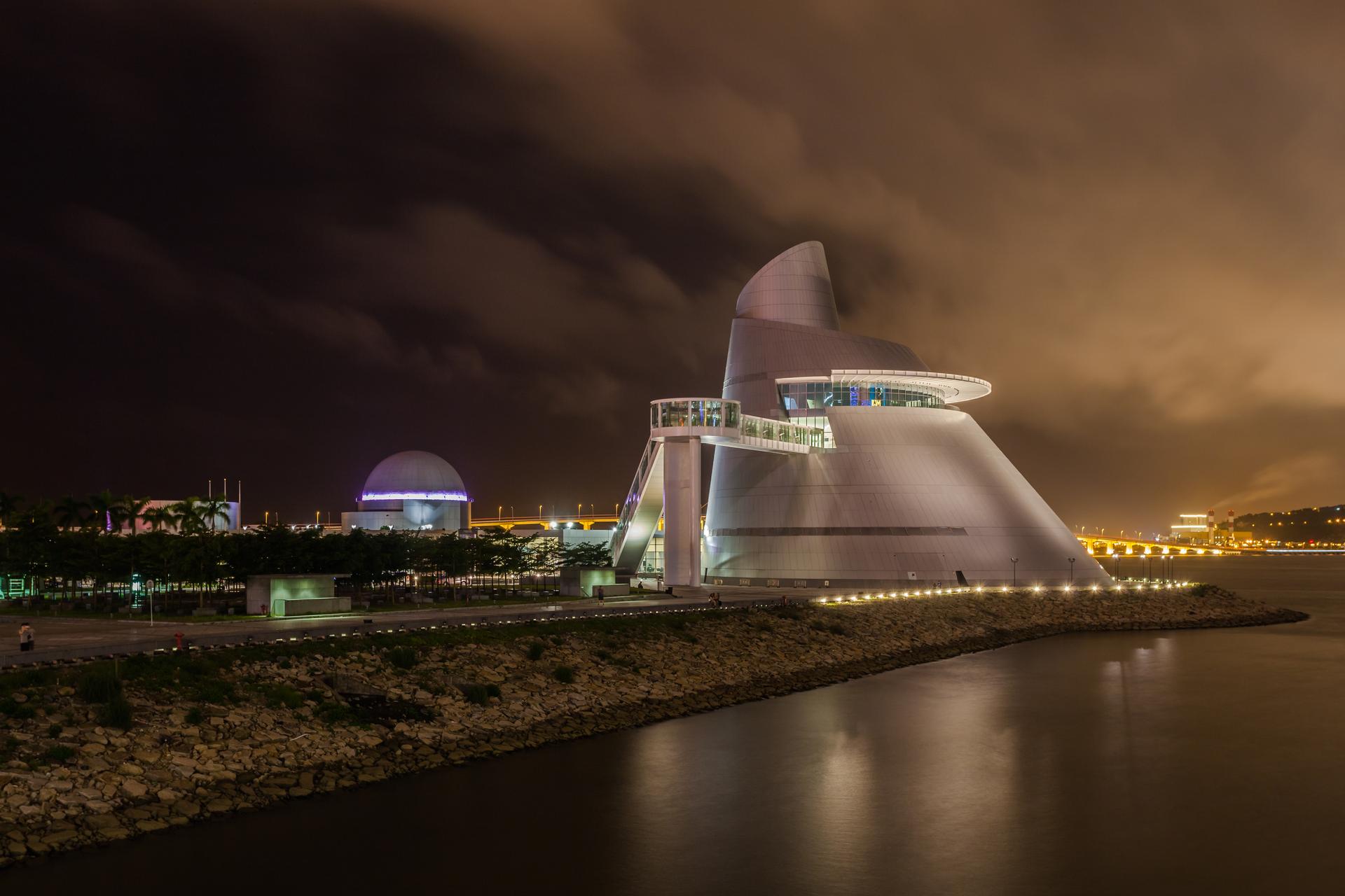 A night time view of the Macau Science Center along the water.