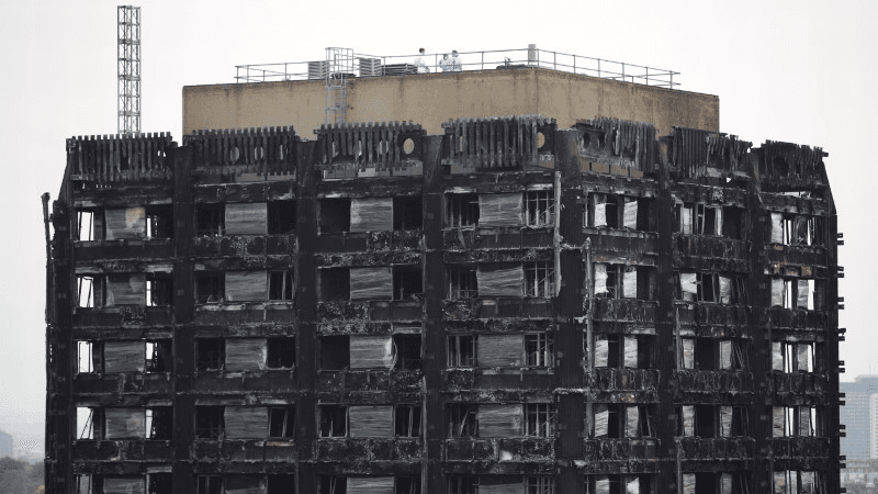 Workers stand on the roof of the burned-out remains of the Grenfell tower in London, Britain, Oct. 16, 2017.