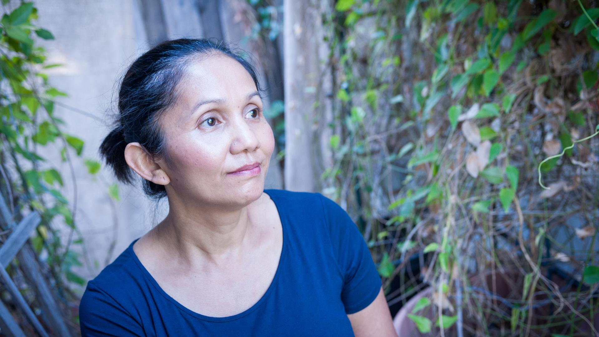 Rotchana Sussman has her hair pulled back and is wearing a blue shirt looking off to the left.