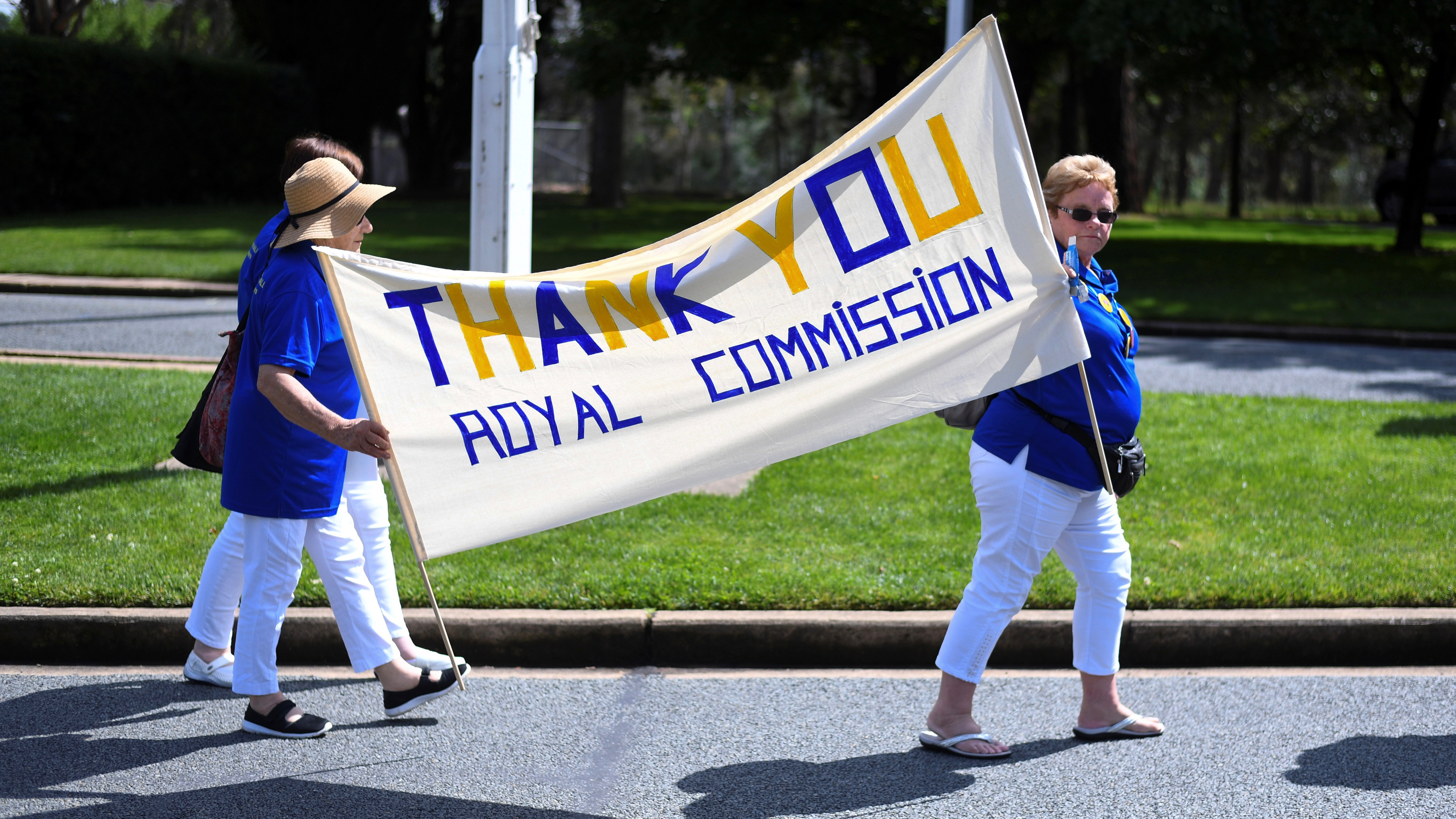 Members of the Care Leavers Australasia Network hold up a banner thanking an Australian government commission on preventing child sexual abuse as they await a final report outside Government House in Canberra, Australia on December 15, 2017.