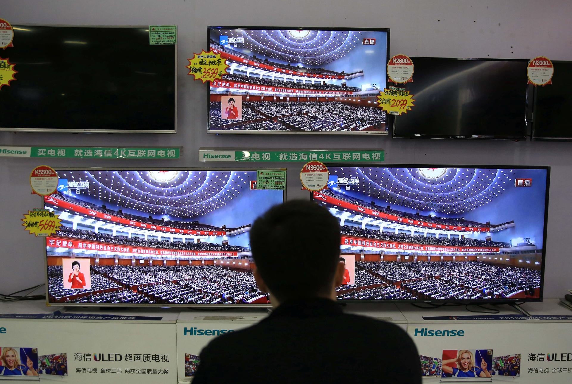 A man watches a broadcast of Chinese President Xi Jinping delivering his speech during the opening of the 19th National Congress of the Communist Party of China.