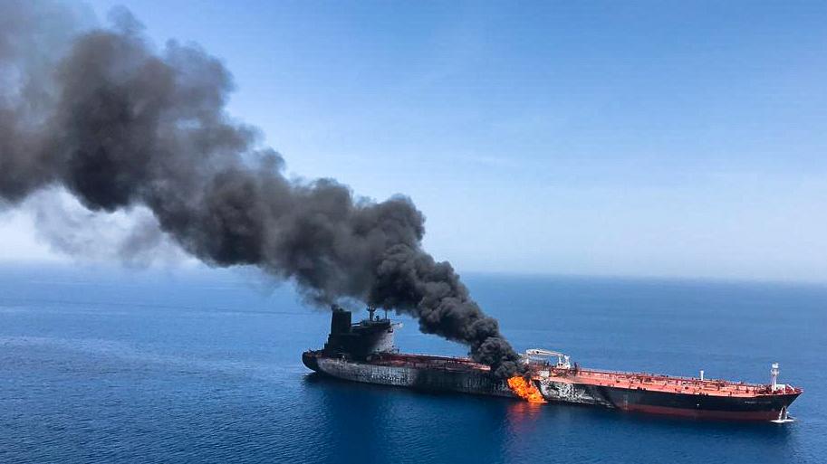 Smoke billows from an open fire it the side of a massive oil tanker out at sea