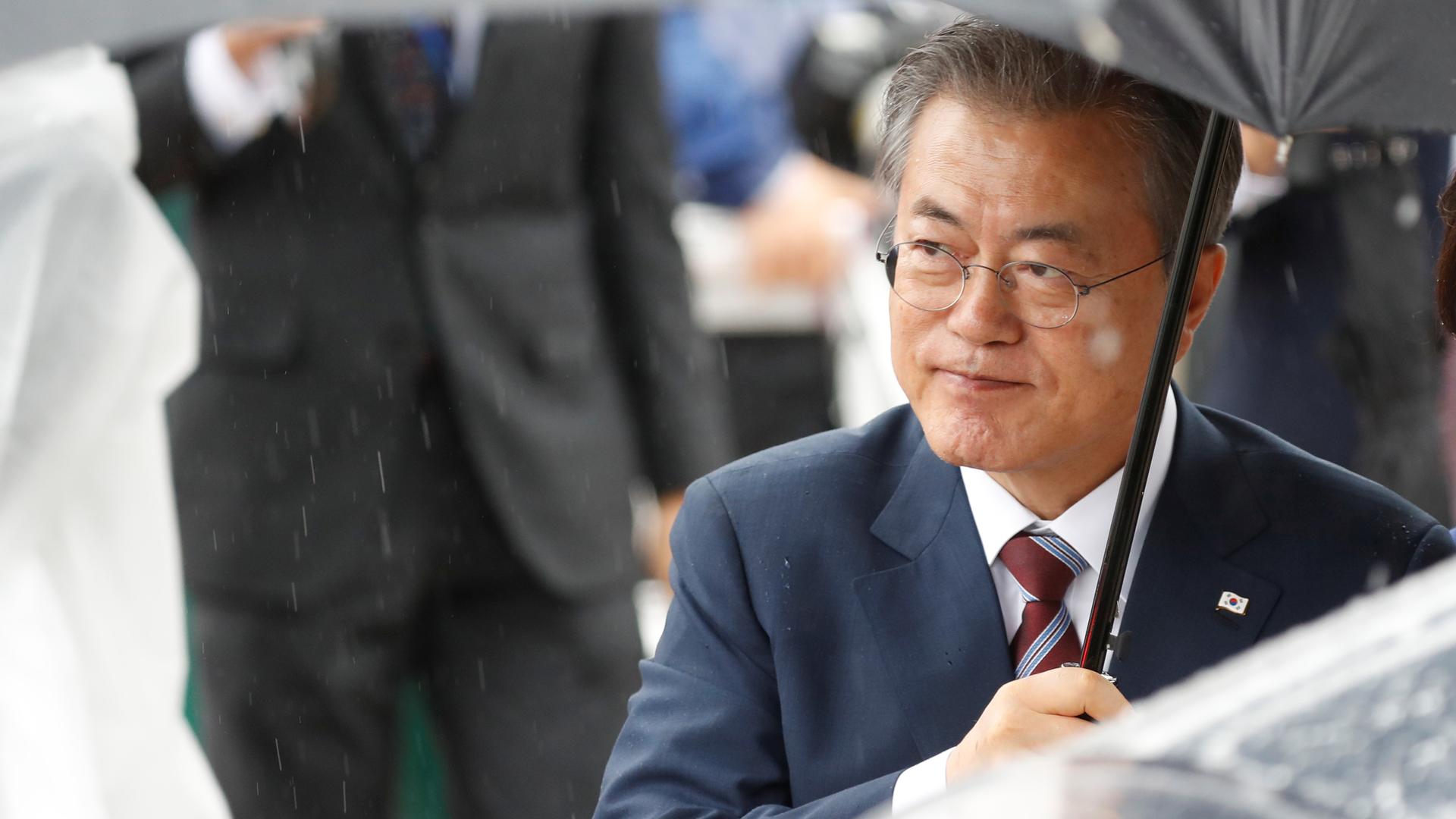 South Korea's Moon Jae-in holds an umbrella over his head