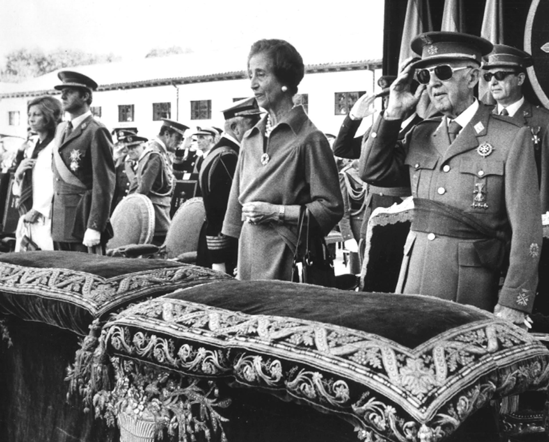 Dictator Francisco Franco stands in military apparel next to his wife at an event.