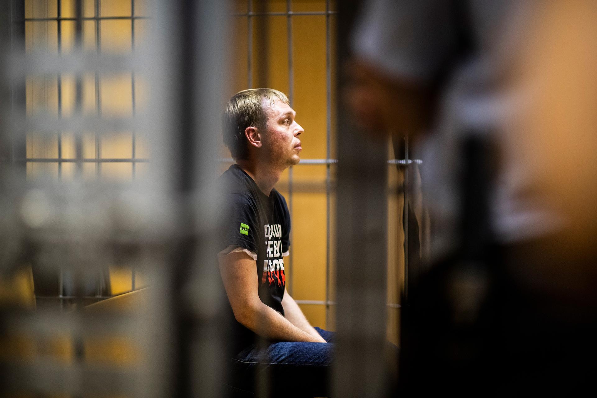 A man sits behind bars