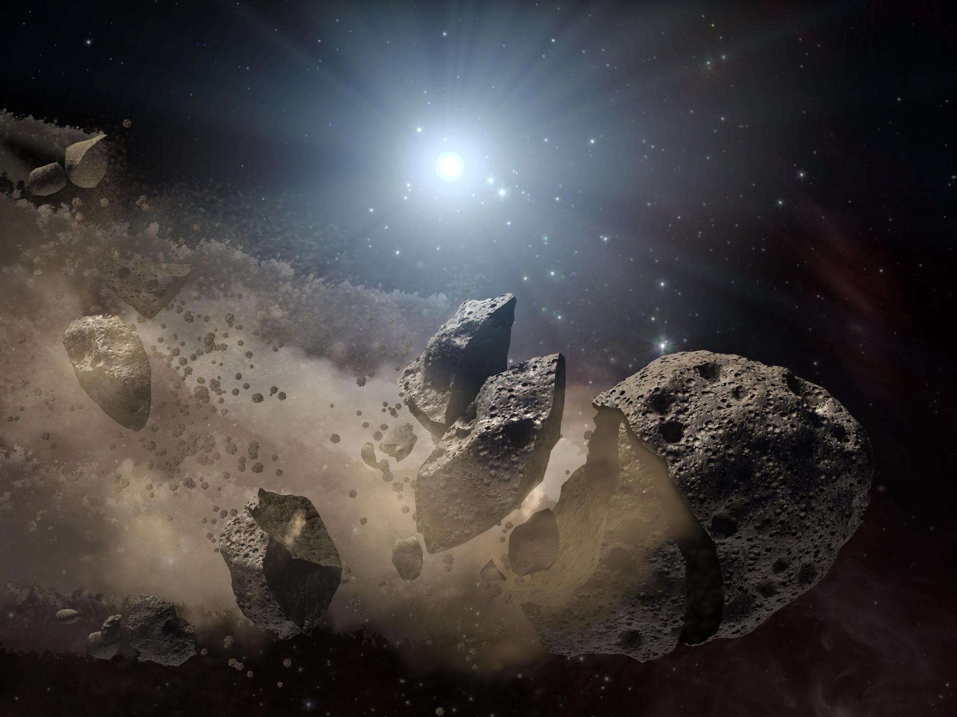 An asteroid breaking into little pieces in space.