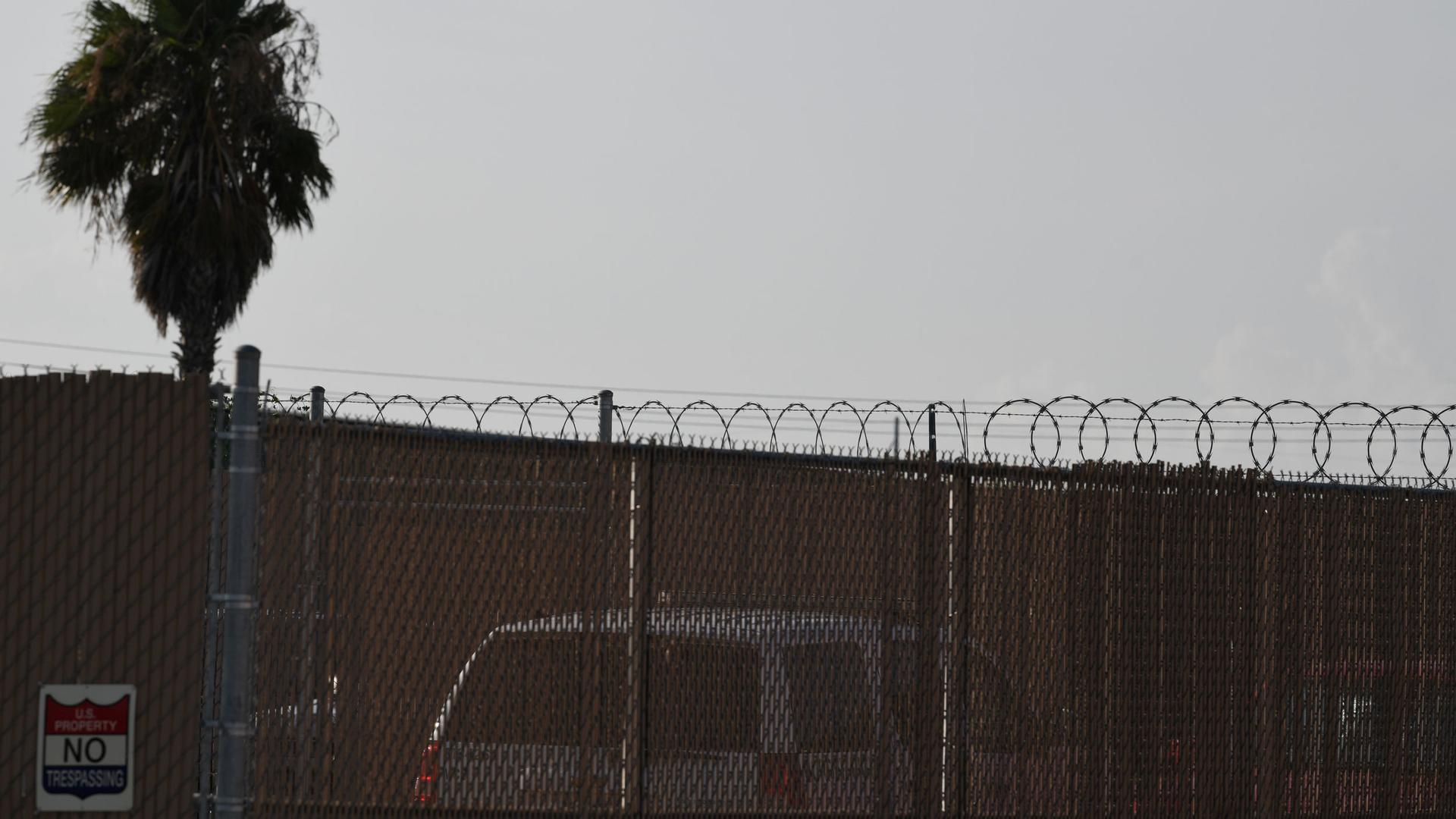 A fenced in building is shown with a sign with the words "US Property No Trespassing" printed on it.