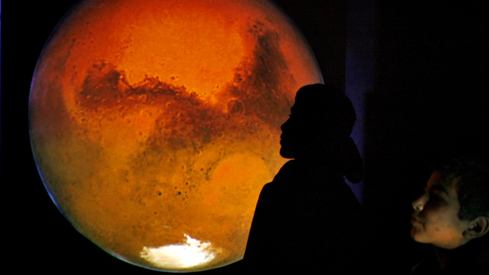 a boy looks at a projection of Mars