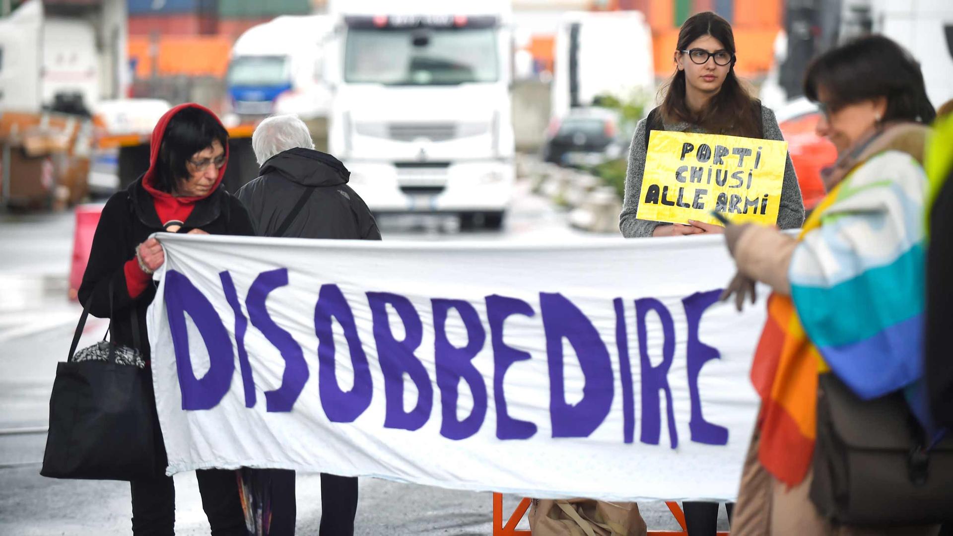 People hold a handpainted banner that reads "Disobbedire."