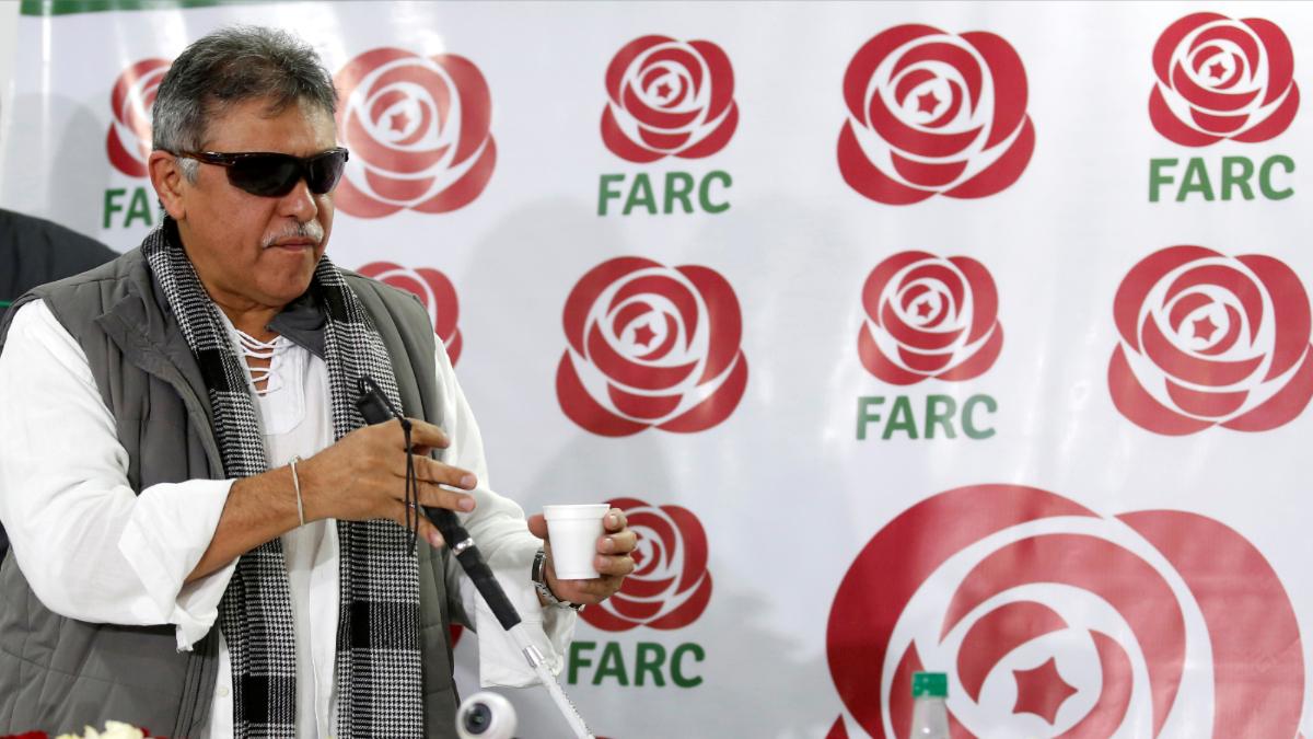 A man walks in front of a banner with the words FARC