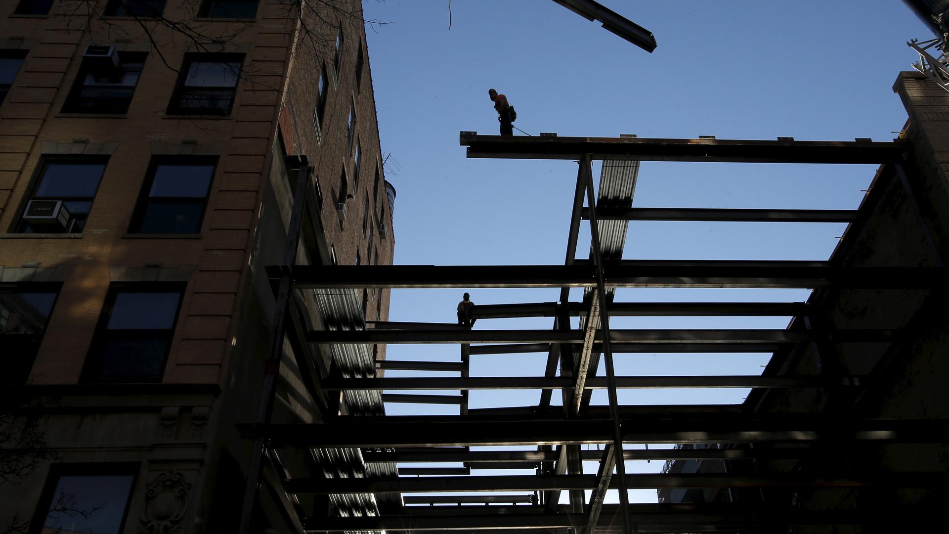 workers install US steel beams against sunlight in construction of building