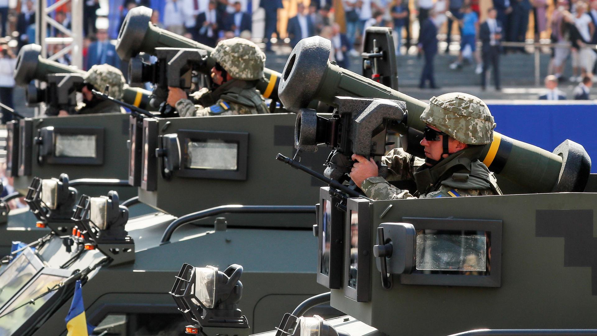 Ukrainian Army servicemembers are shown dressed in combat helmet and sunglasses while riding with Javelin anti-tank missiles.