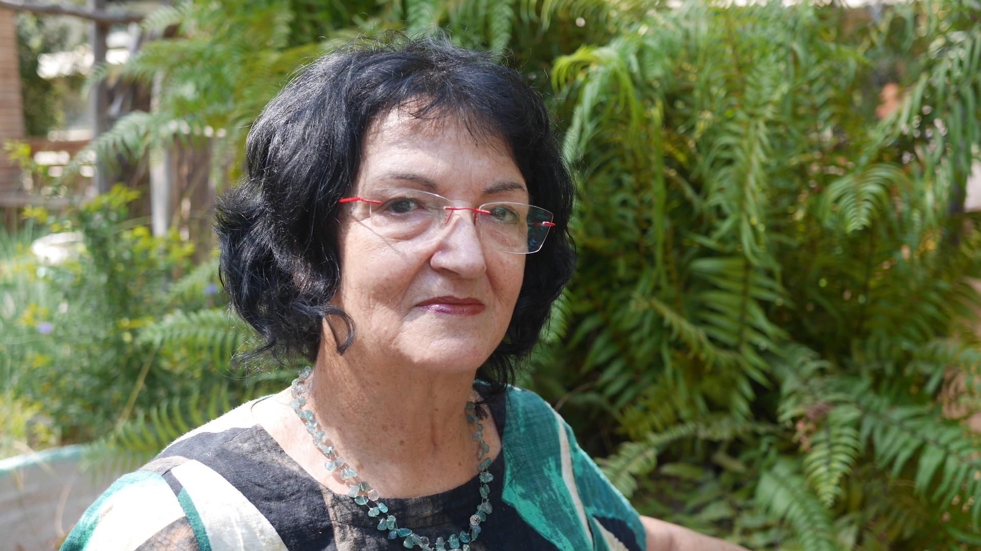 A 69-year-old woman with black hair poses for the camera