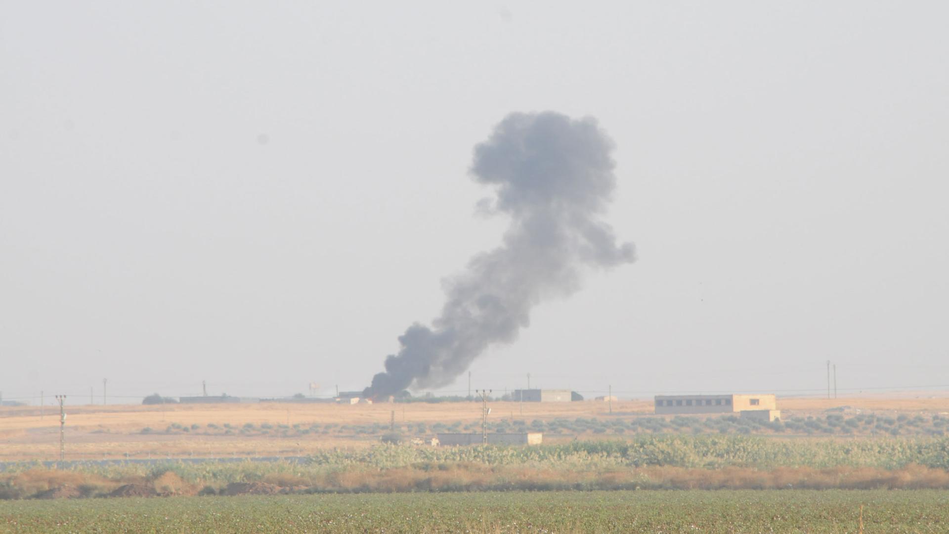 Smoke rises from a structure shown off in the distance.