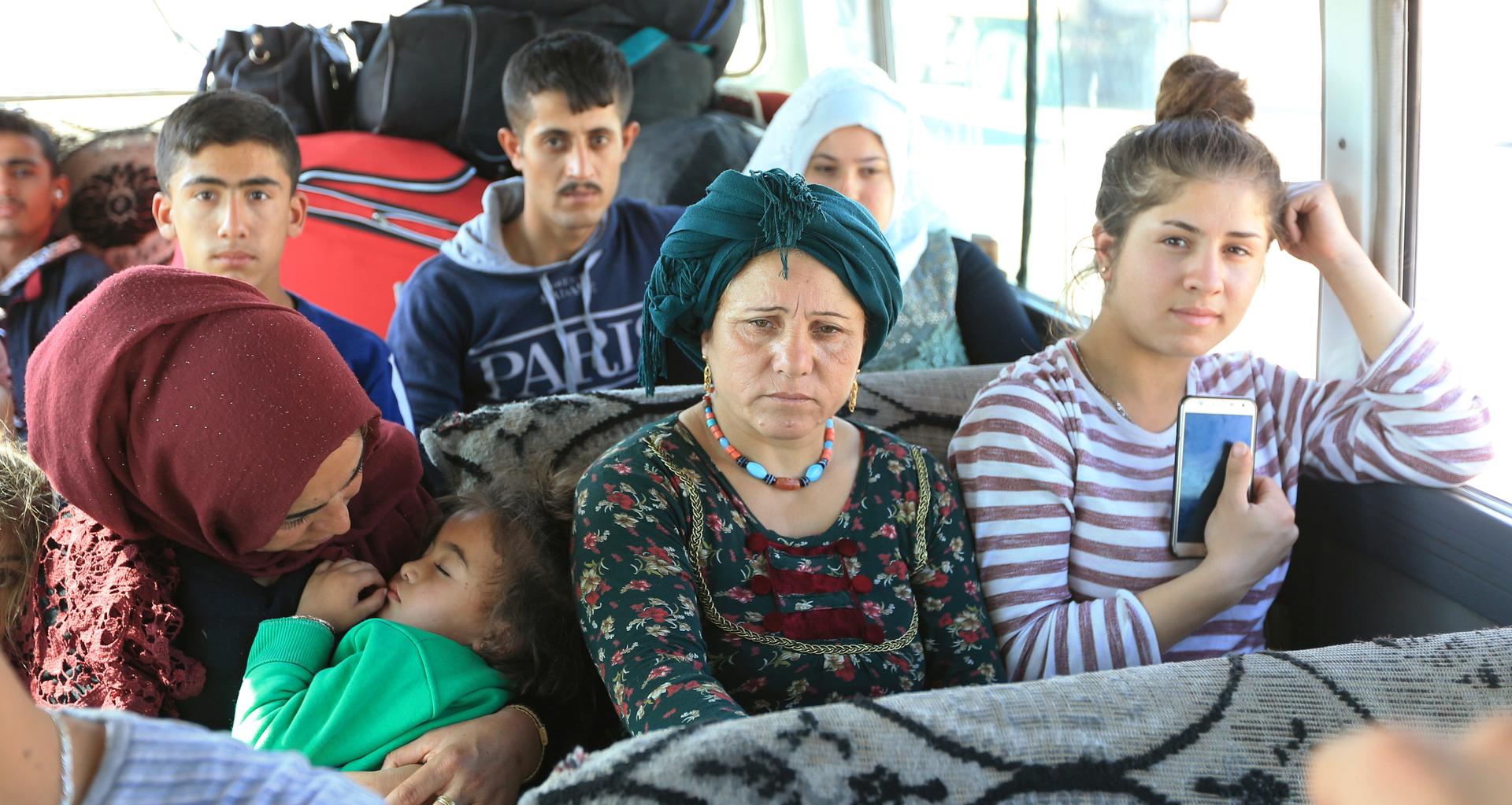 Syrian displaced families who fled violence after the Turkish offensive against Syria, sit in a bus on their way to camps on the outskirts of Dohuk, Iraq, on October 16, 2019.