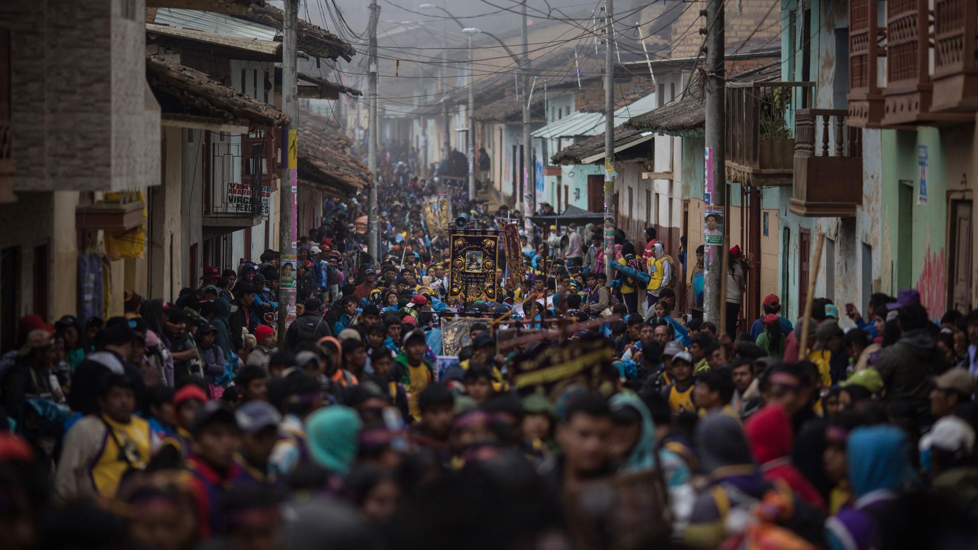 Piura Street in Ayabaca, Peru, is shown filled with people the entire length of the photo with buildings on either side.