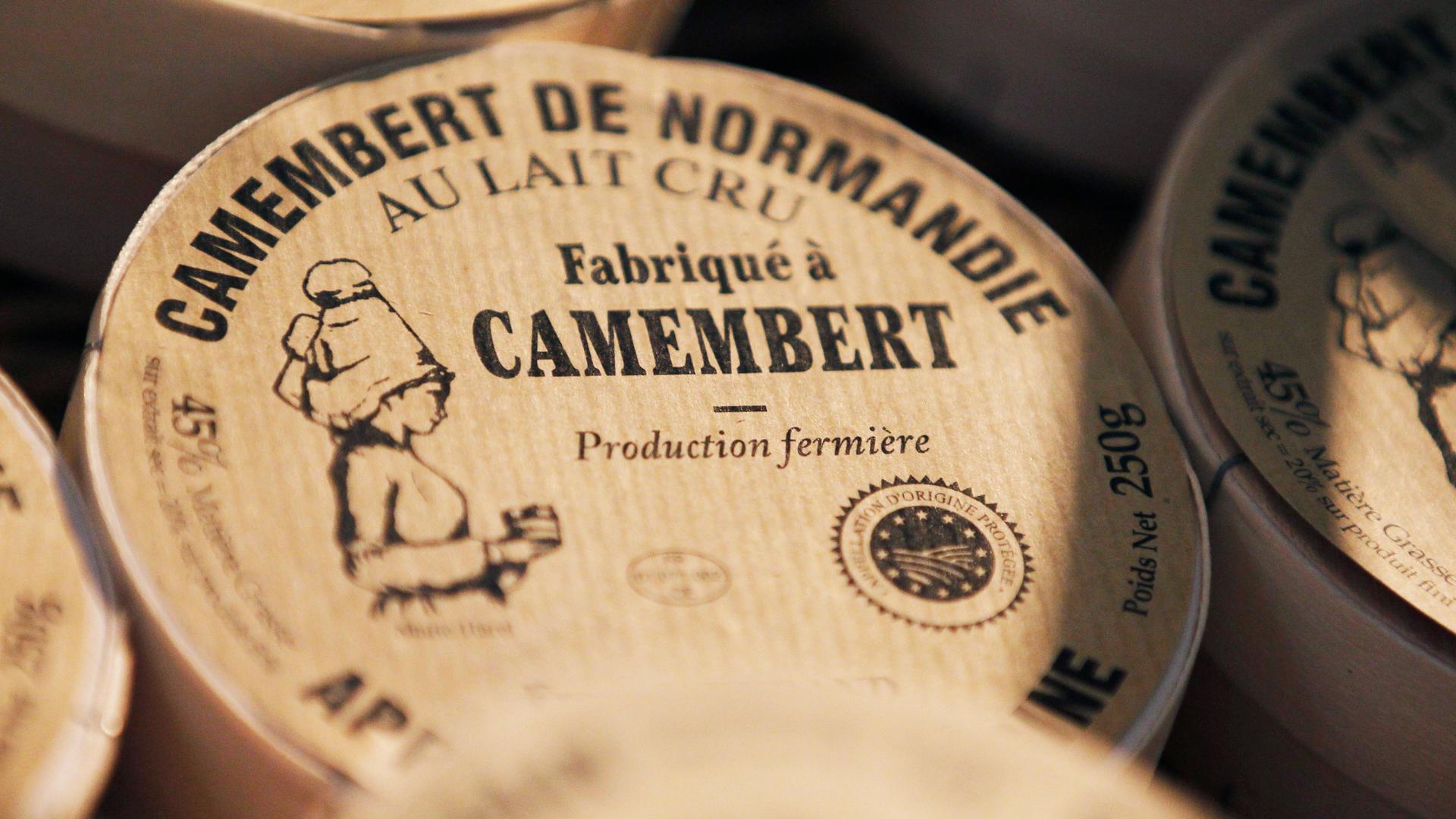 A round box of a French Camembert cheese is shown in a close-up photo with the words, "Camembert de Normandie" printed on it.