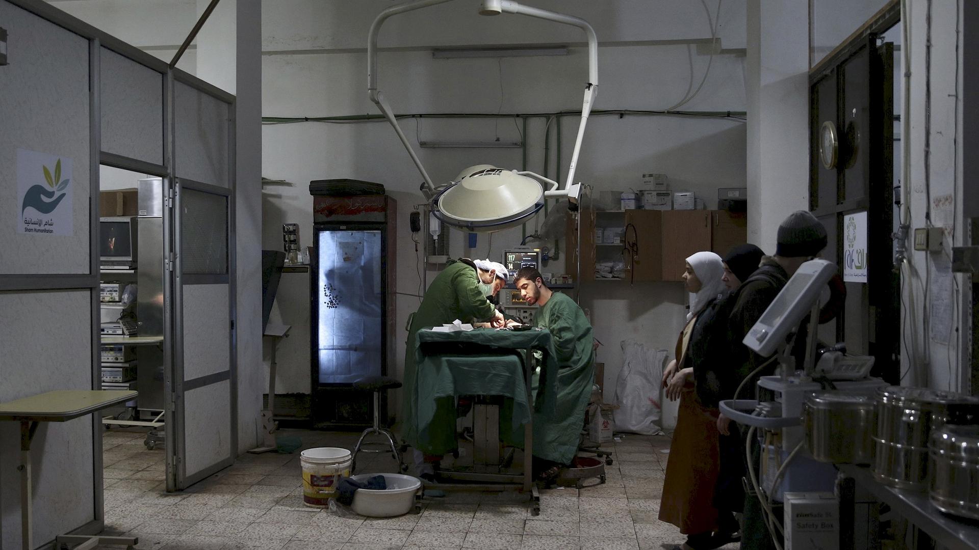 Doctors operate under a dim light in a clinic.